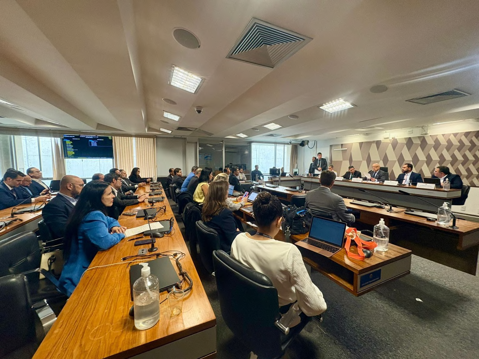 Visão ampla da sala com participantes em torno das mesas.