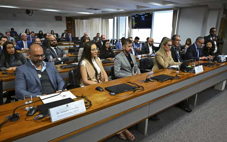 Participantes sentados nas fileiras da sala de reunião.