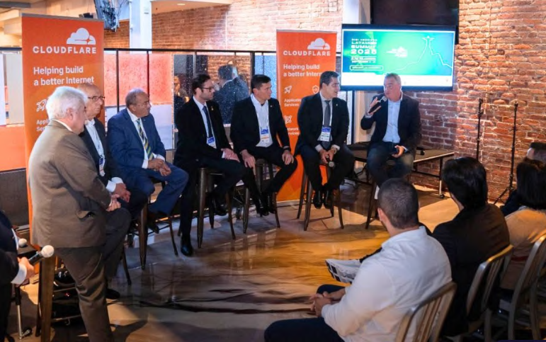 Participantes de um painel em ambiente de conferência.