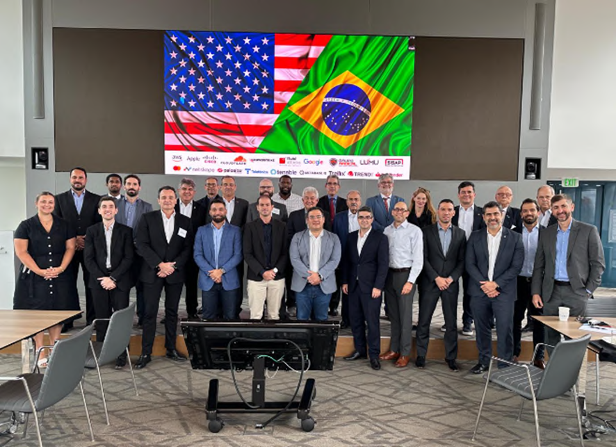 Comitiva reunida diante de uma projeção com as bandeiras do Brasil e dos Estados Unidos.